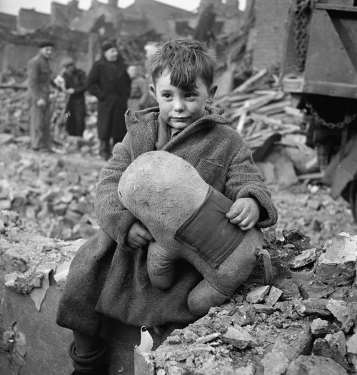 [Abandoned boy holding a stuffed toy animal amid ruins following German aerial bombing of London, by Toni Frissell, 1945